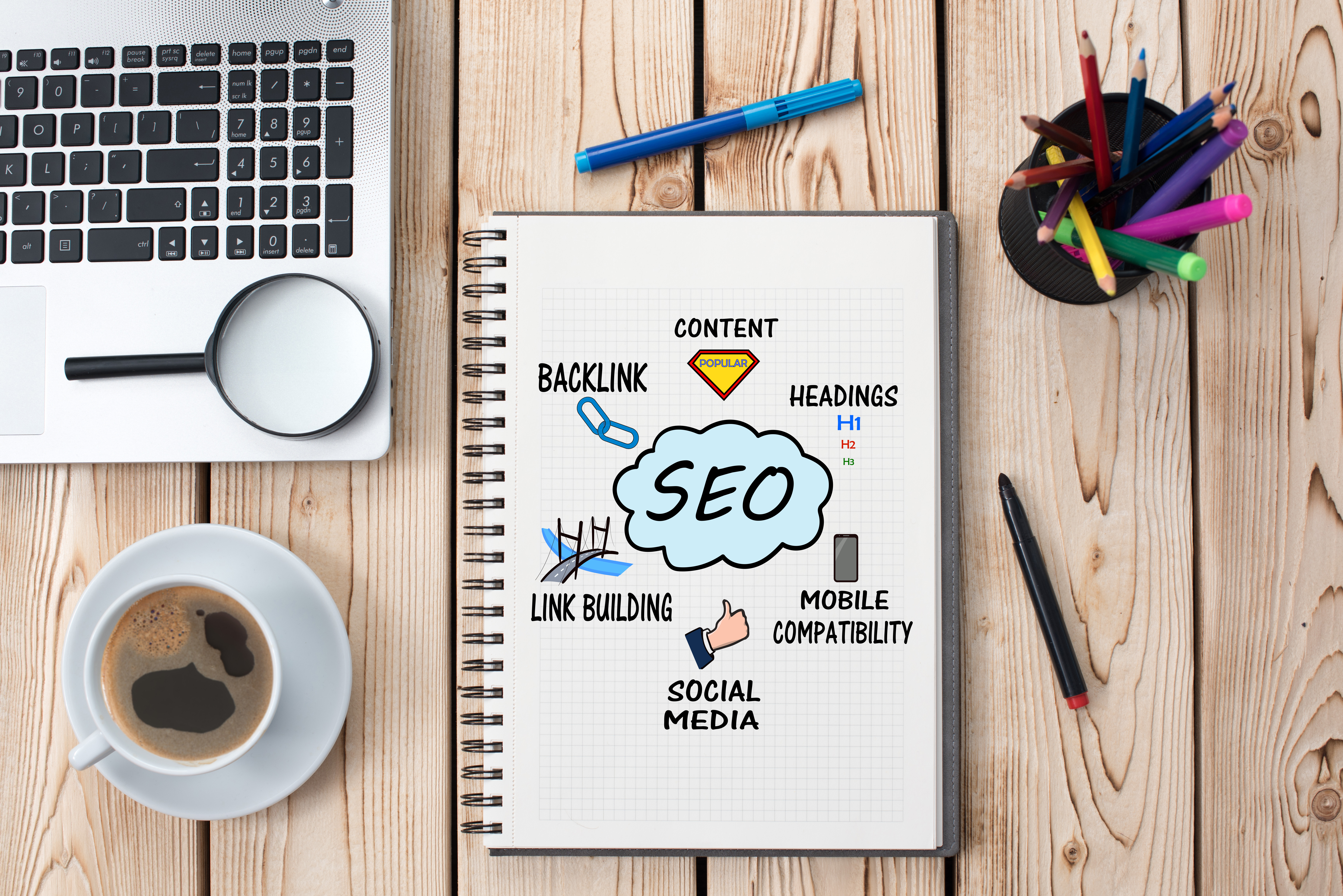 Picture of a notebook on a desk with the cover of the notebook depicting all the components of Search Engine Optimization (SEO)  